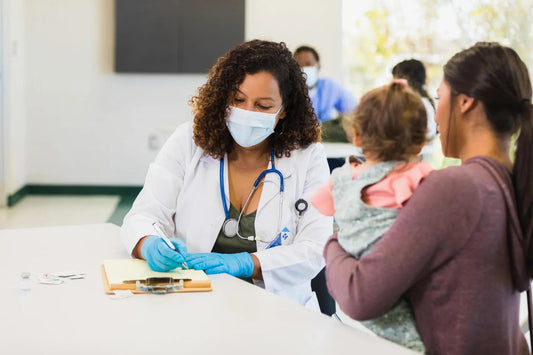 Mother holding baby at pediatrician clinic during vaccination, highlighting importance of child vaccine schedule and immunization for infants.